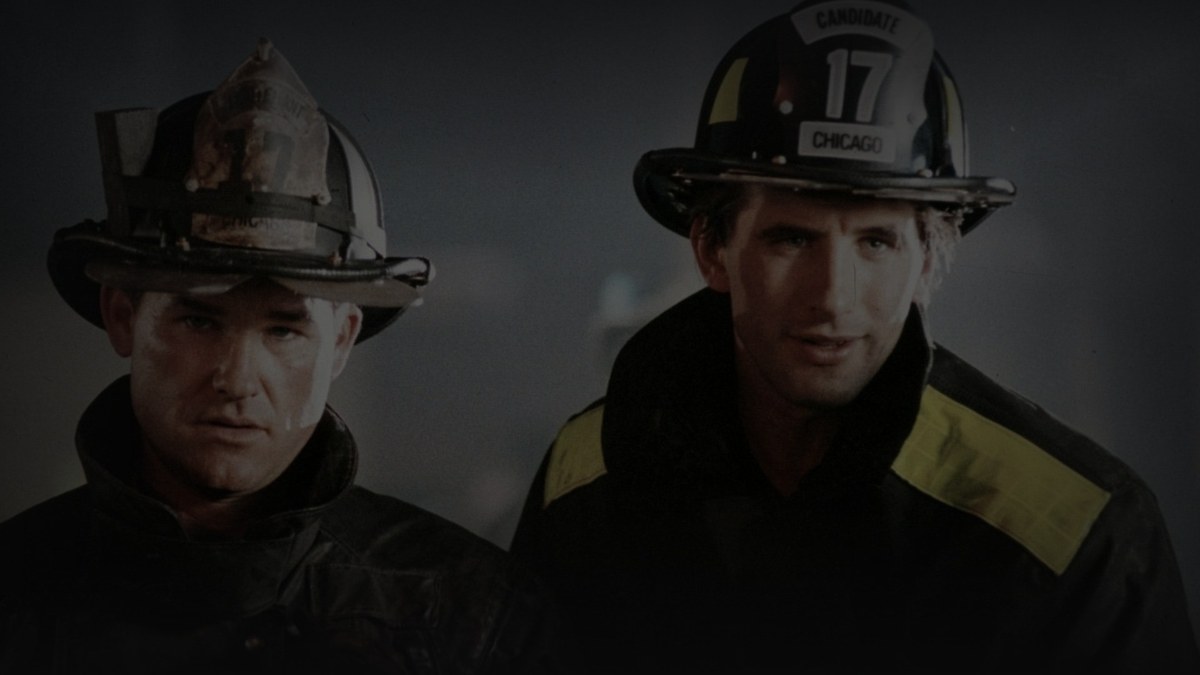 Still from Backdraft (1991) — tmdb backdrop (id 2924); genuine still of kurt russell and william baldwin in firefighter gear. pre-darkened source to 0.72 (source luma 106.3) and baked through scripts/bake_dark_photo.py at factor 0.45, 1200x675, on-disk luma 27.5
